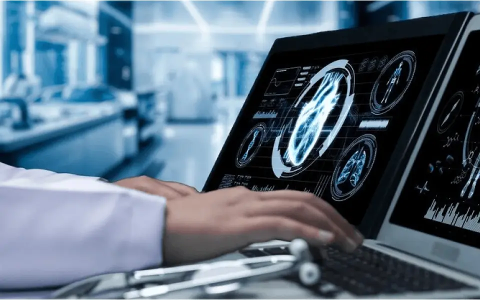 Close-up of a doctor's hand using a laptop displaying MRI images