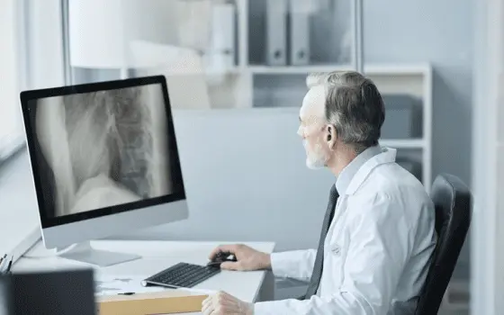 senior-male-doctor-sitting-at-desk-examining-backbone-scan-with-focused-expression