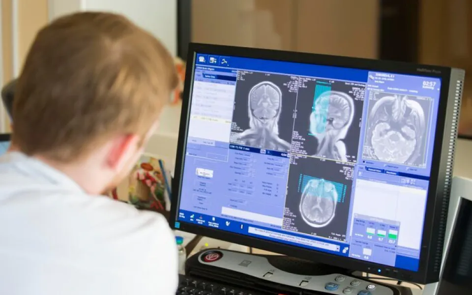 Doctor analyzing multiple head scans with detailed imaging data displayed on a medical monitor for diagnosis