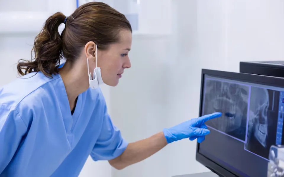 Young female doctor pointing at a screen displaying medical scan images