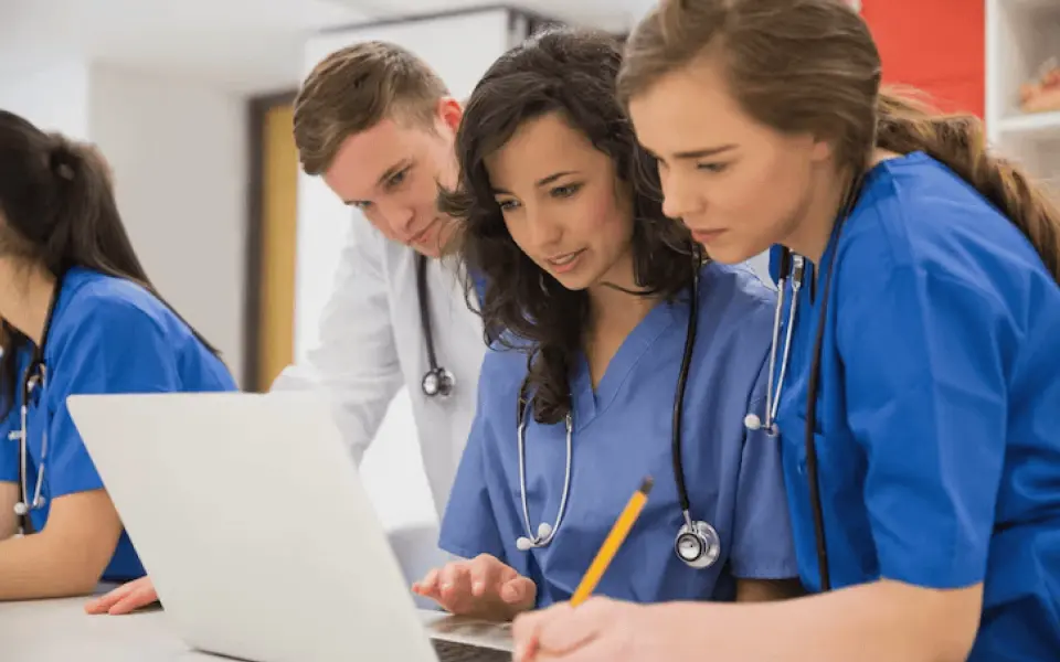 Three medical students looking at a laptop displaying medical images