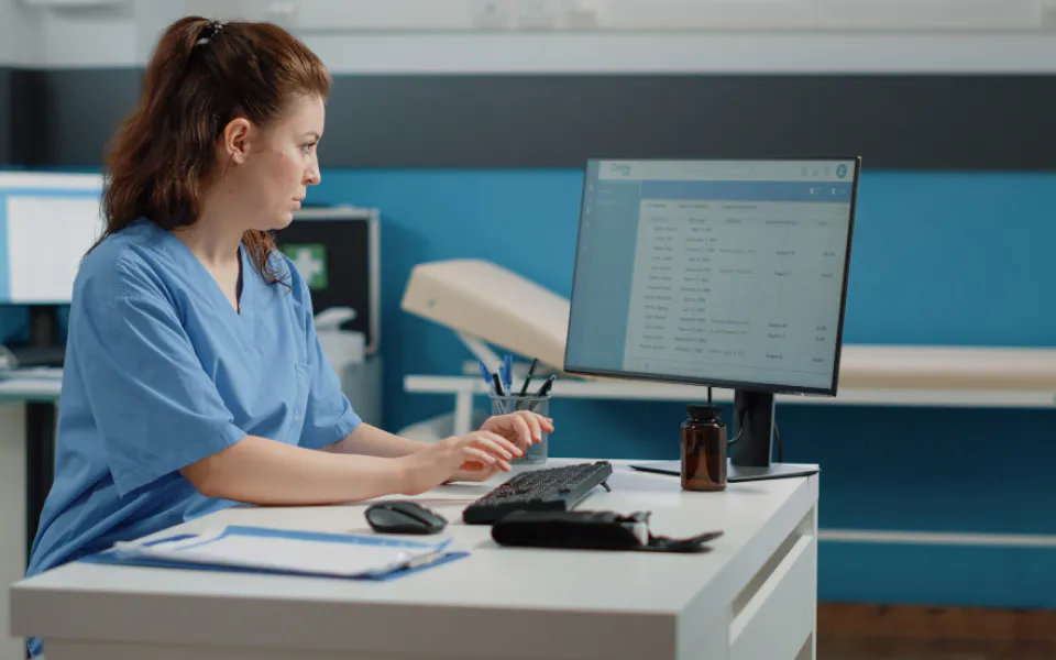 Female doctor typing at desk, using Scriptoware’s Medical Image Integration API for seamless imaging access.