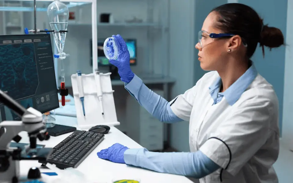 Female lab staff evaluating a sample with live analytics displayed on screen
