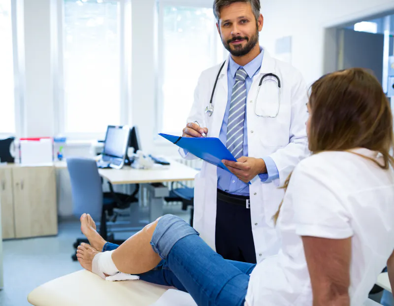 Doctor assisting orthopedic patient with leg cast, documenting with Scriptoware’s imaging tools.