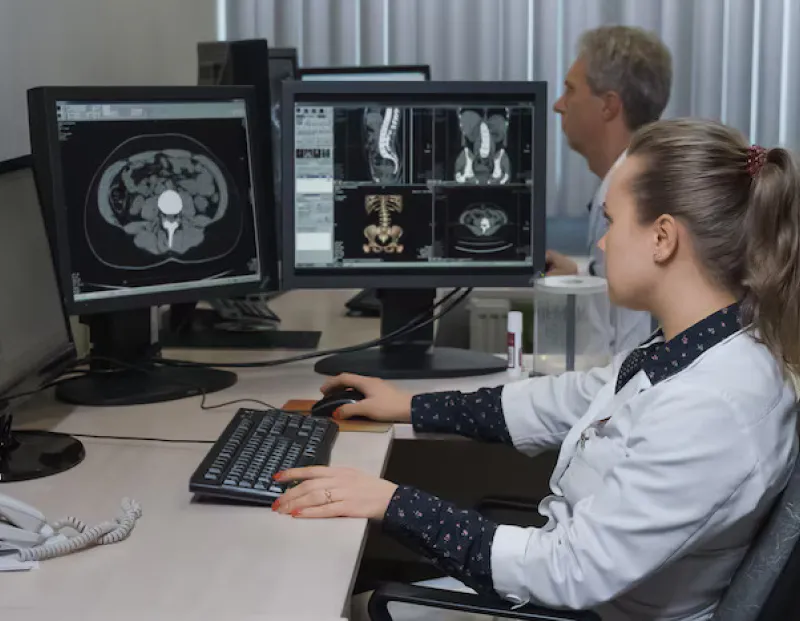 Male and female doctors reviewing patient scans on monitors using Scriptoware’s orthopedic PACS.