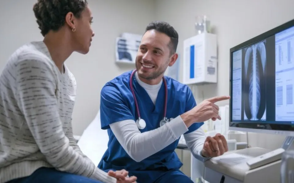 Doctor and patient happily discussing while looking at MRI scan images on a screen