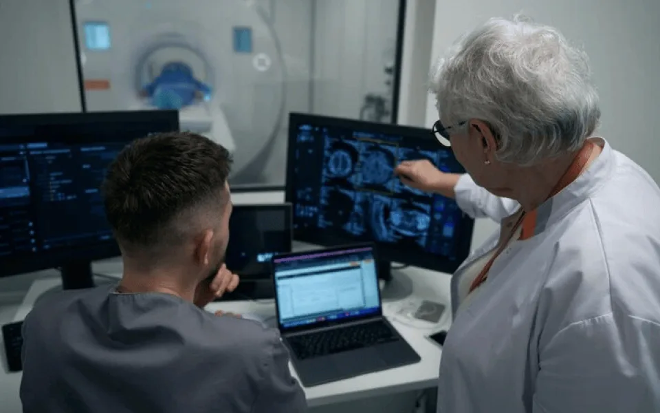 Senior radiologist pointing at a screen displaying brain MRI scans