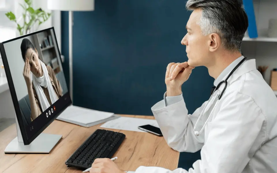 Virtual consultation with a doctor listening to a patient’s complaint at a desk